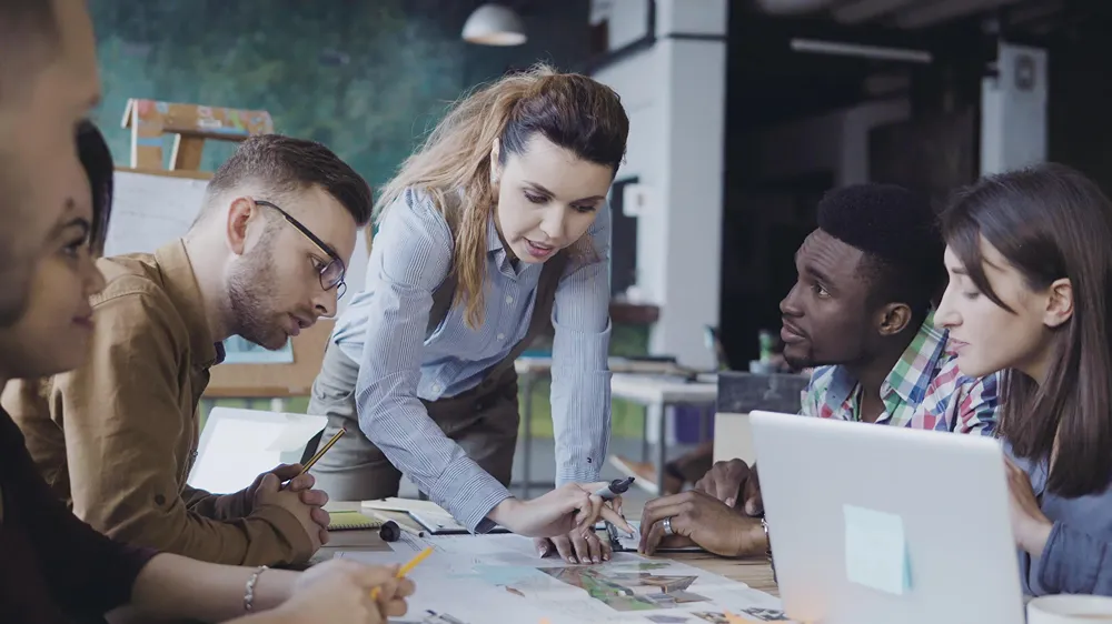 A diverse team of professionals is collaborating on a project, with a manager leading the discussion