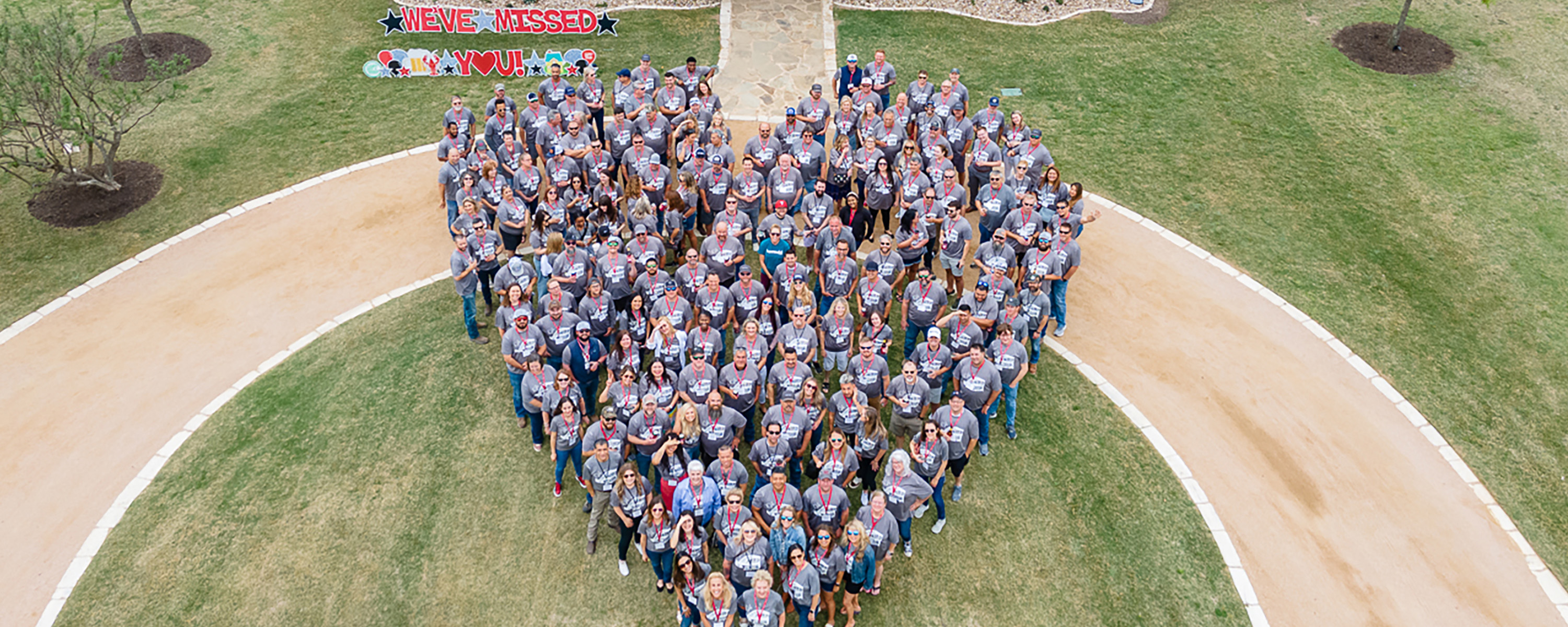 over head picture of team standing in the shape of a heart