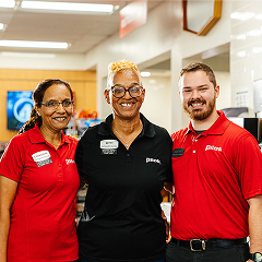 Three diverse and smiling Pilot Flying J team members are posing together in a store.
