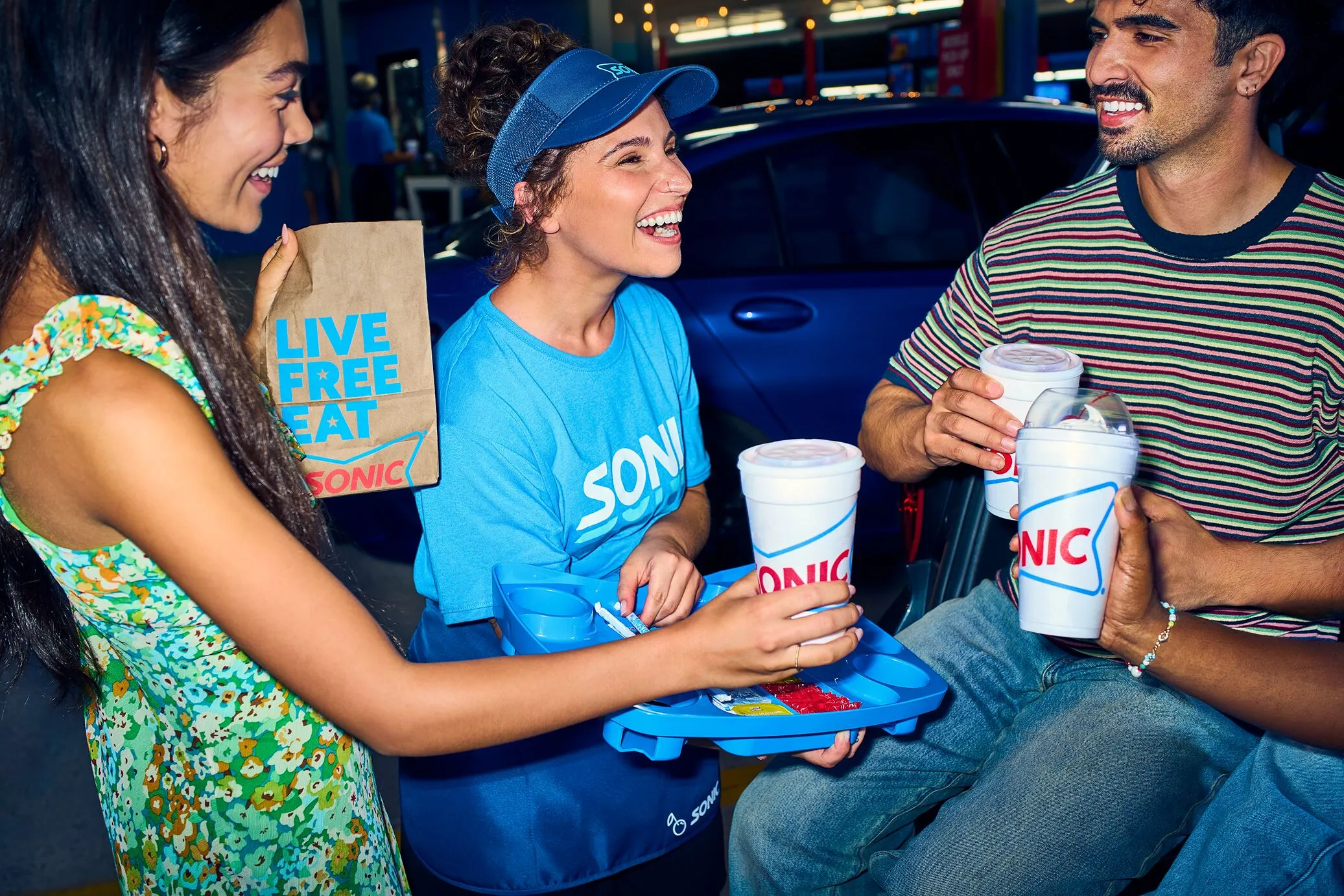 Drive-thru employee handing drinks to a customer with a smile
