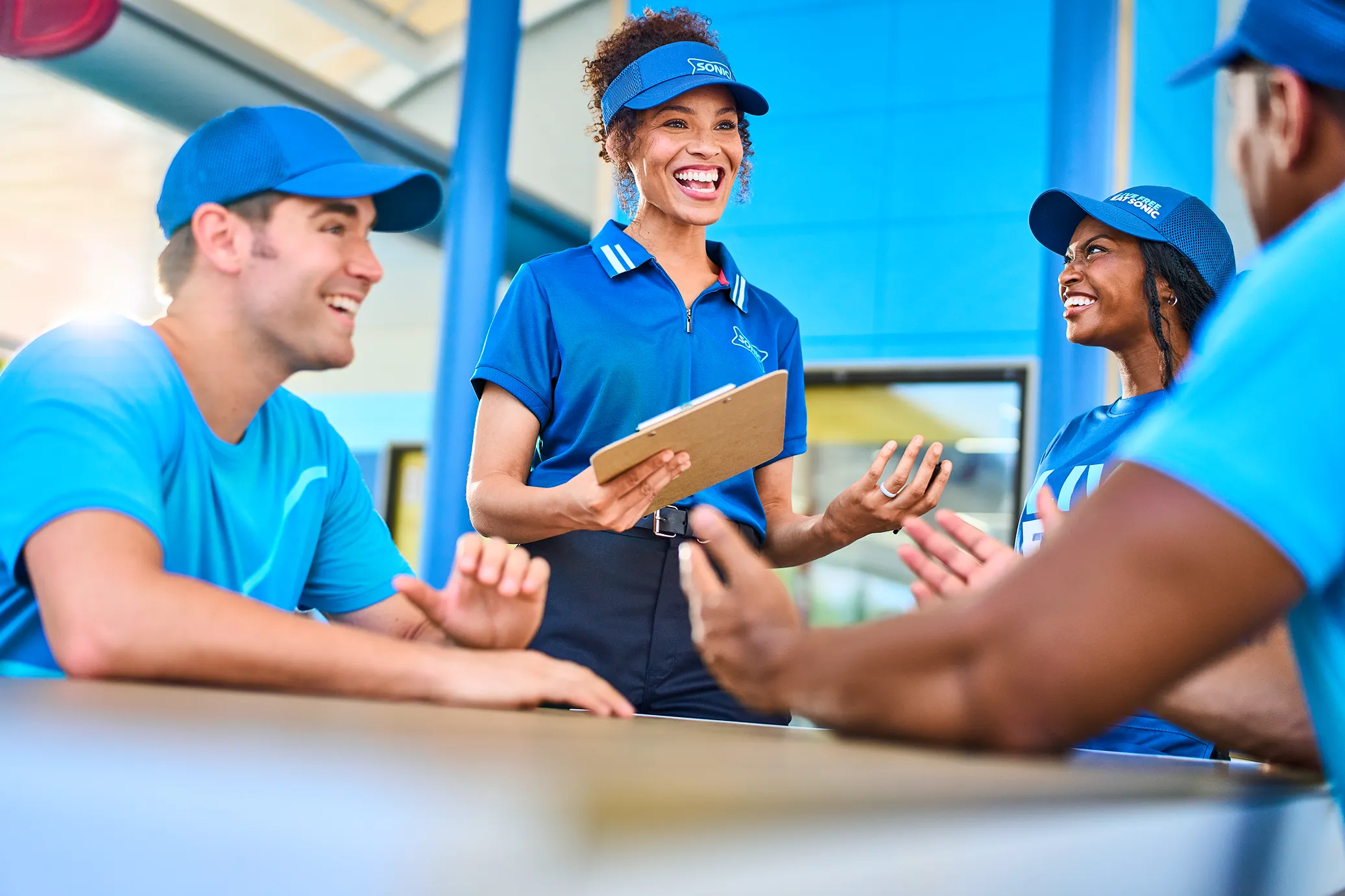 Two Sonic employees smiling and having a conversation.