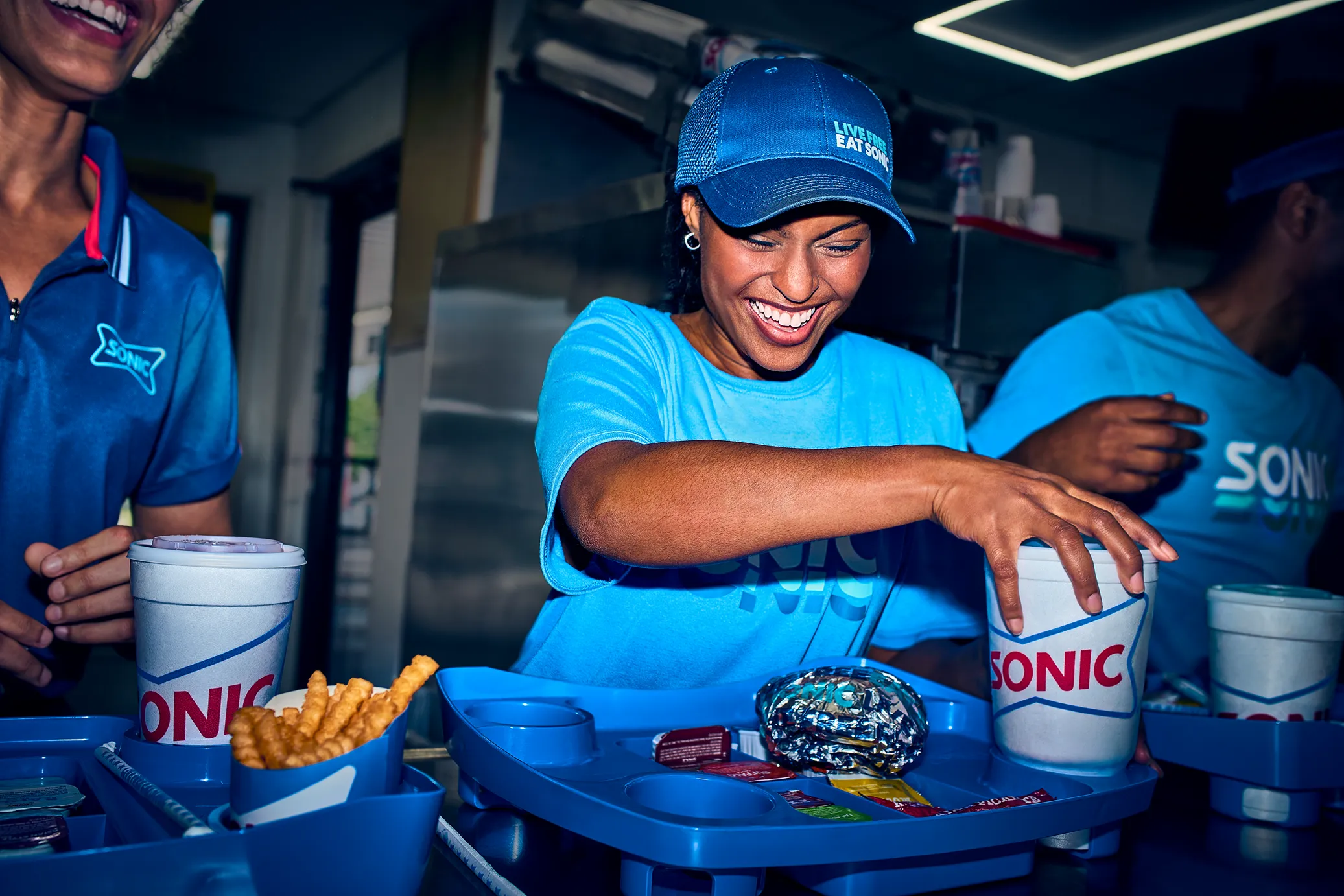 Confident Sonic employee with arms crossed in an outdoor seating area.