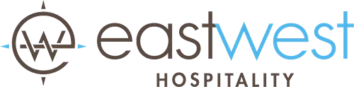 EastWest Hospitality logo with circular emblem and blue text