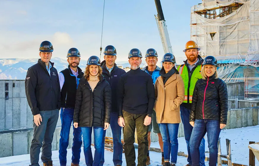 Group of people in hard hats at construction site smiling