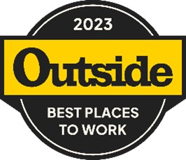 Woman celebrating on trophy labeled "Outside Best Places to Work" by East West Partners