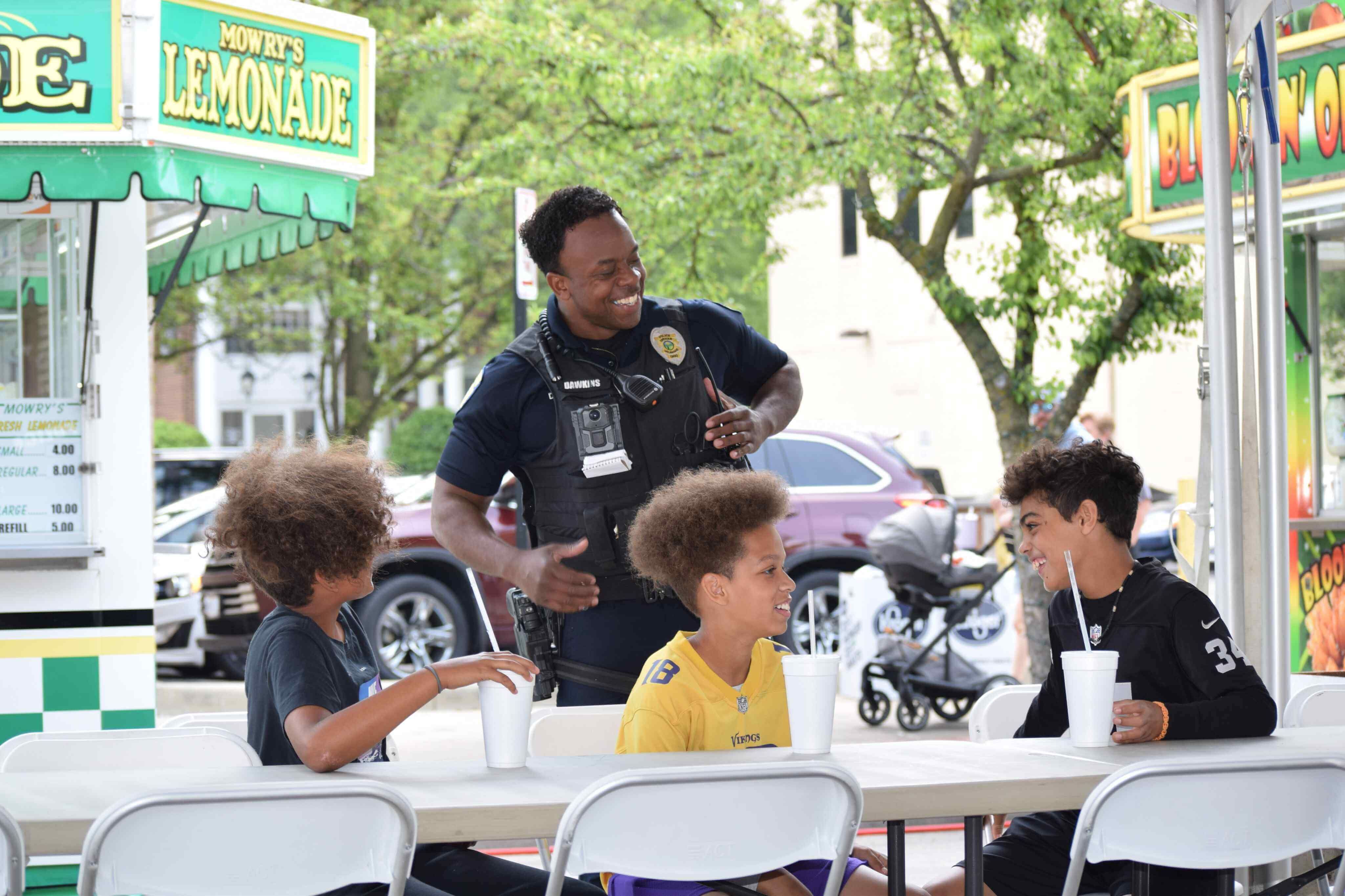 A male police officer was laughing and joking with the children