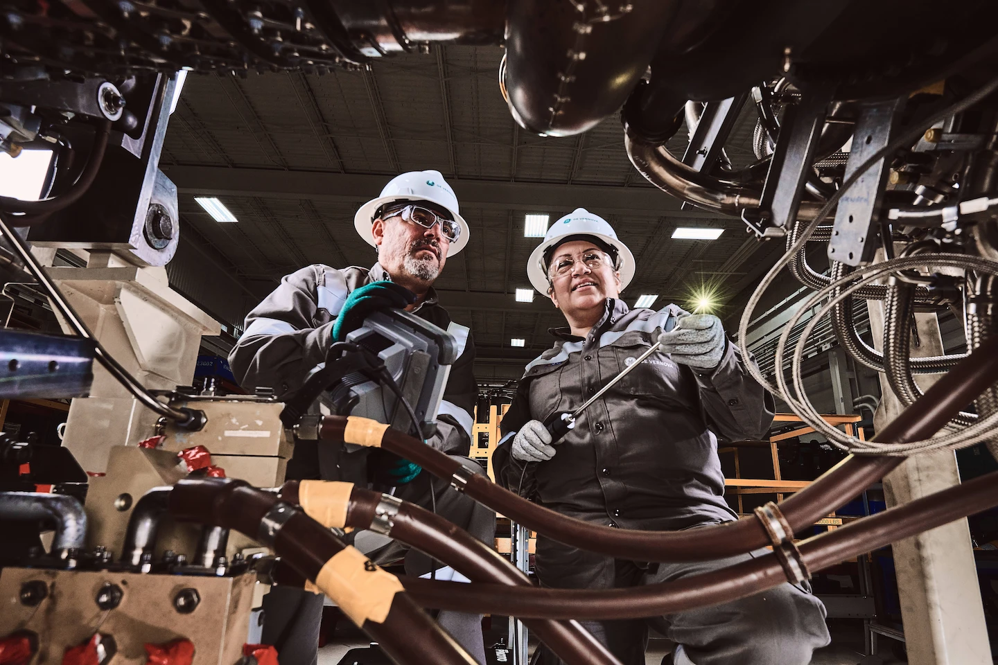 A group of people wearing safety equipment working on a piece of machinery