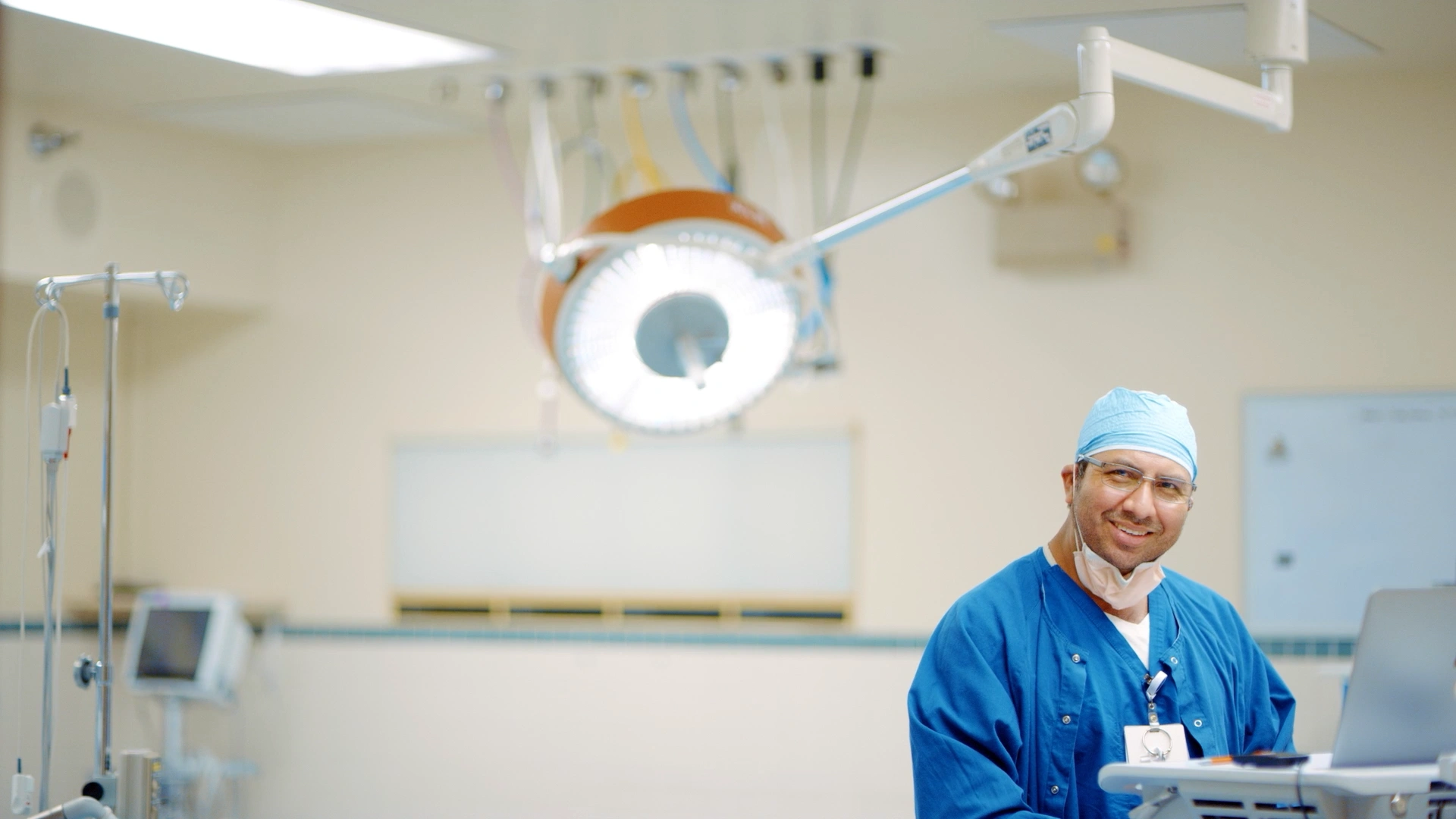 Smiling nurse in blue scrubs with stethoscope standing in hospital hallway