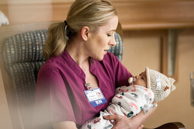 A photo of a nurse cradling a new born baby in their arms