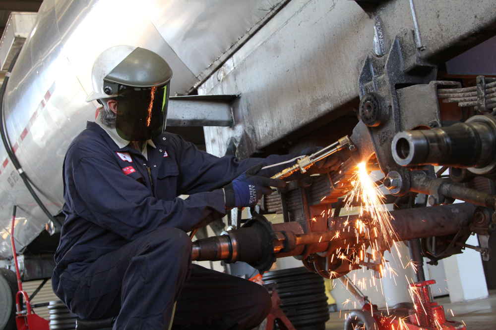 shop employee working on truck with torch equipment