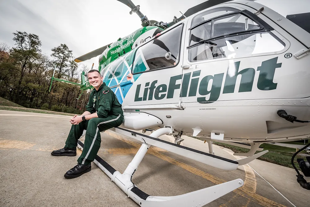 A smiling paramedic sits on a LifeFlight helicopter