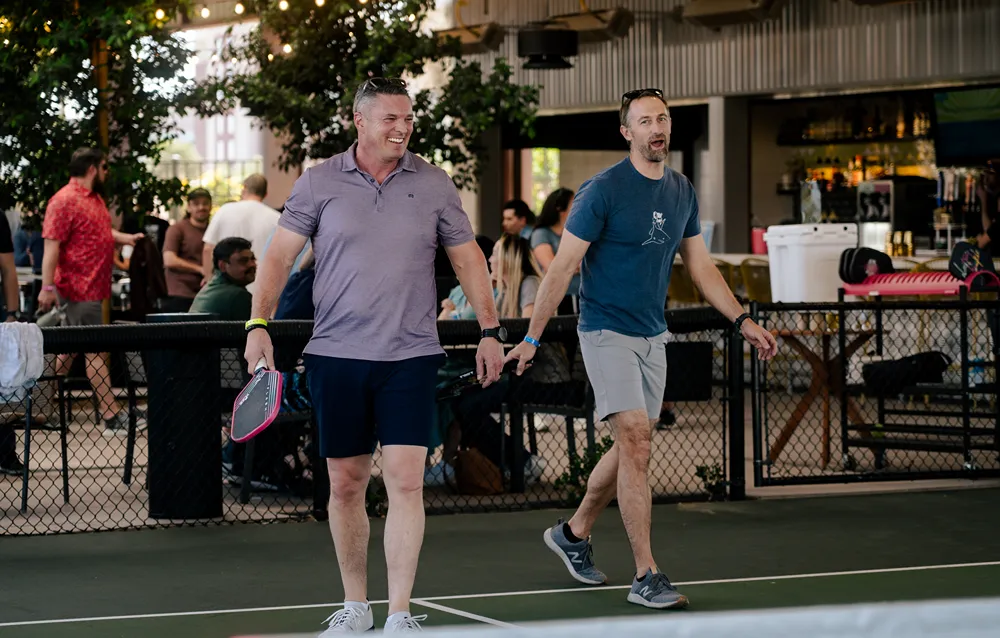 some man posing and holding pickleball rackets