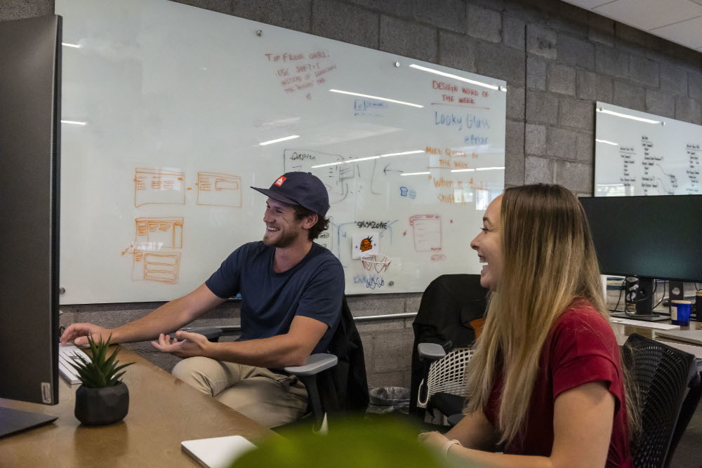 two employees smiling at a desk